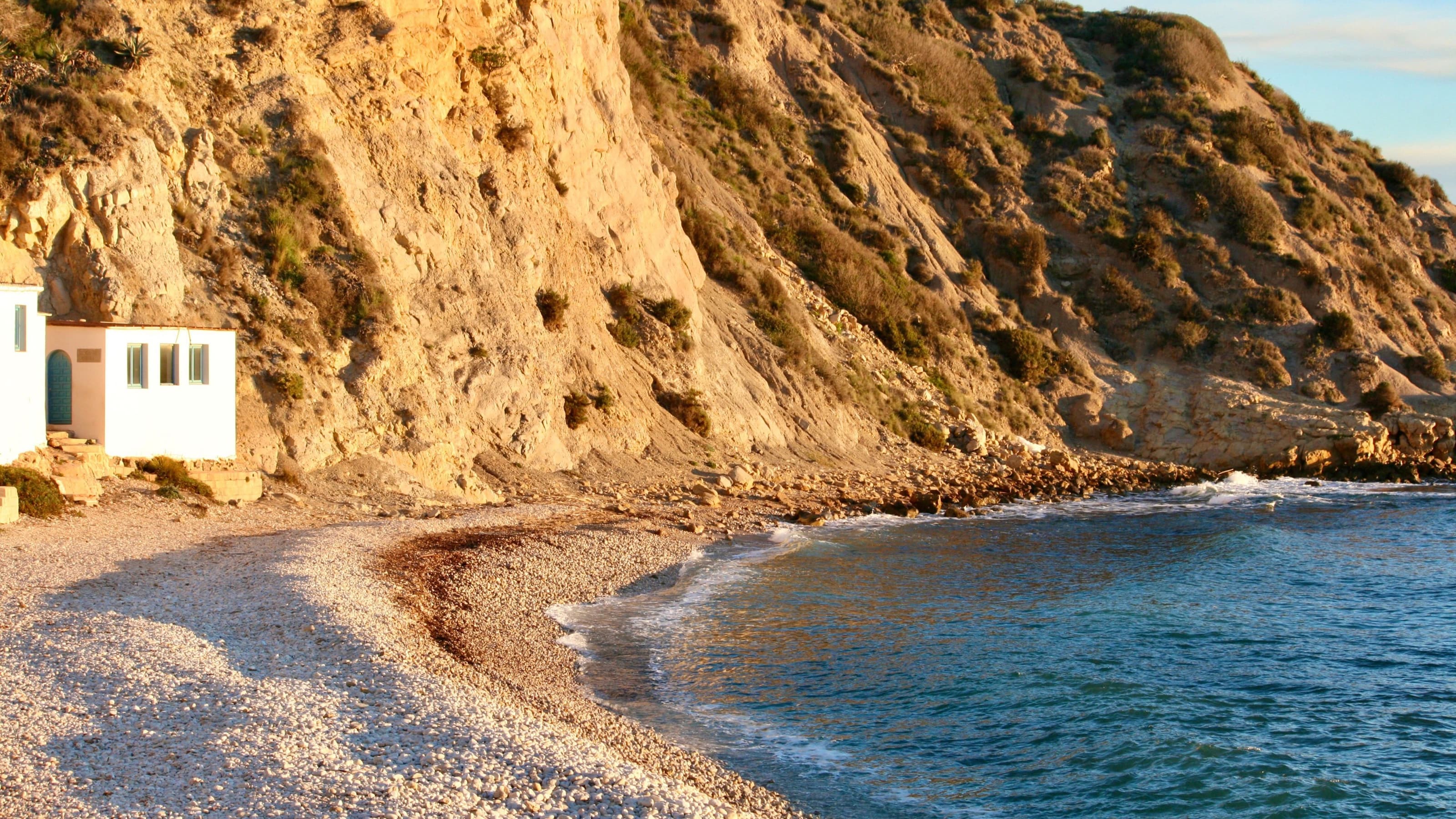 La cabane de pêcheurs blanche à porte bleue de la cala du Portitxol, à Xàbia, au lever du jour